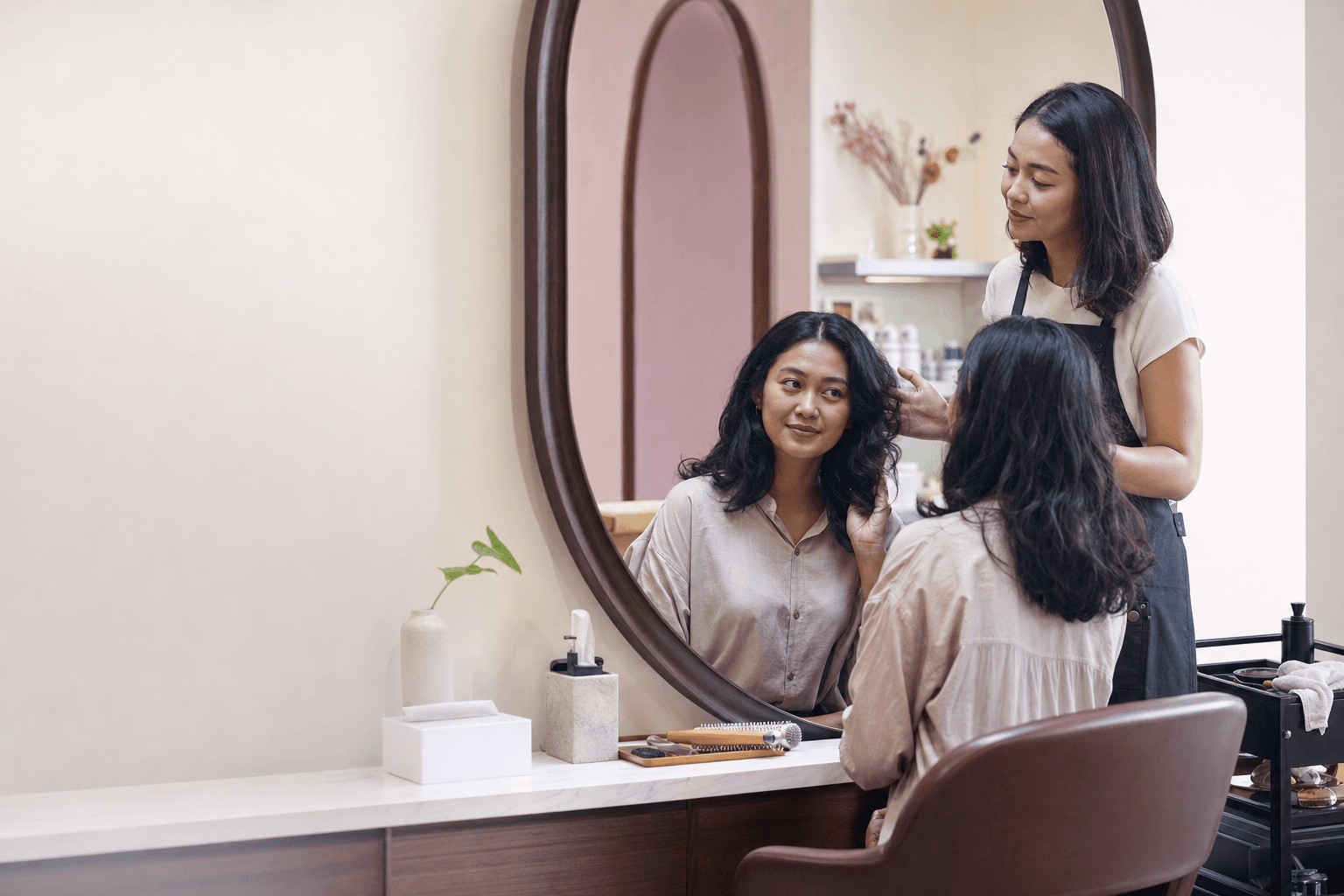 Stylist dan pelanggan perempuan Indonesia sedang berkonsultasi di salon